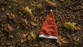 Holiday season is coming soon. A conceptual background photo of Santa Claus hat on yellow leaves in fall. Last day of autumn and