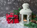 Holiday shiny christmas composition. Burning candle lamp with red gifts, pine cone, berries and fir tree.