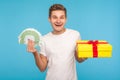 Holiday shopping, bonuses! Happy cheerful smiling man in white t-shirt holding gift box and euro banknotes, ready to buy present Royalty Free Stock Photo