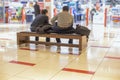 Holiday shopping men with women concept. two unrecognizable tired men are sitting on a bench in a shopping center