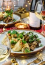 Holiday snacks with zucchini and eggplant rolls on wooden table served with plates, glasses, bottle of wine, candles, festive Royalty Free Stock Photo