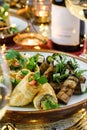 Holiday snacks with zucchini and eggplant rolls on wooden table served with plates, glasses, bottle of wine, candles, festive Royalty Free Stock Photo