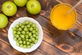 Holiday of summer harvest background with copy space. Yellow honey in glass bowl with spoon. Green gooseberries in white