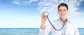Holiday summer sea medical insurance concept, smile doctor woman showing stethoscope, in sea blue sky background Royalty Free Stock Photo