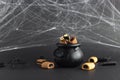 holiday sweets in a witch\'s cauldron and next to it on a black background with cobwebs