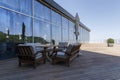 Holiday tables, chairs, a sofa and closed umbrellas on the porch