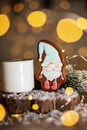 Holiday traditional food bakery. Gingerbread little fairytale gnome in cozy decoration with garland lights and cup of hot coffee