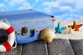 Holiday travel suitcase, lifebuoy and shells on wooden table Royalty Free Stock Photo