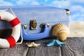 Holiday travel suitcase, lifebuoy and shells on wooden table Royalty Free Stock Photo