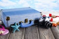 Holiday travel suitcase, photo camera, lifebuoy and shells on wooden table Royalty Free Stock Photo