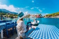 Holiday vacation. Woman in cafe enjoying time in Assos village in front of emerald bay of Mediterranean sea white boat