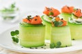 Holiday vegetable appetizers. Cucumbers rolls with soft cheese, pieces of salted salmon, microgreens and black sesame served on a Royalty Free Stock Photo