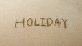 Holiday word written on sand shore beach with incoming wave Royalty Free Stock Photo