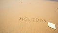 Holiday written in the sand at the beach with post it Royalty Free Stock Photo