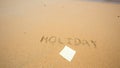 Holiday written in the sand at the beach with post it Royalty Free Stock Photo