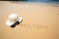 Holiday written in the sand at the beach waves in the background Royalty Free Stock Photo