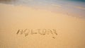 Holiday written in the sand at the beach waves in the background Royalty Free Stock Photo
