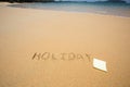 Holiday written in the sand at the beach waves in the background Royalty Free Stock Photo