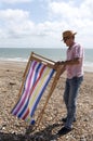 Holidaymaker erecting a deckchair on the beach