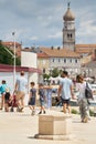 Holidaymakers on the promenade in the harbor in front of the old town of Krk in Croatia