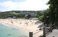 Holidaymakers and sunbathers on Newquay beach with azure seas.