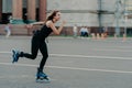 Slim healthy European woman rollerskates on high speed photogaphed in motion dressed in black clothing poses against