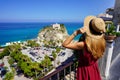 Holidays in Calabria. Back view of beautiful fashion girl enjoying view of Tropea village on Coast of the Gods, Calabria. Summer