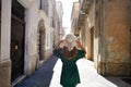 Holidays in Calabria, Italy. Back view of beautiful stylish tourist girl walking between narrow alleys of Pizzo Calabro historic