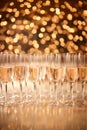 Holidays celebration. Champagne flutes with sparkling wine on golden bokeh lights background. Peach fuzz Color of Year 2024