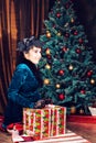 Holidays, celebration and people concept - smiling woman in dress holding red gift box over christmas tree lights Royalty Free Stock Photo