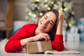 Holidays, celebration and people concept - smiling woman wearing red sweather and jeans holding gold gift box over Royalty Free Stock Photo