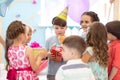 Holidays, childhood and celebration concept - happy friends giving presents to birthday child at party in daycare