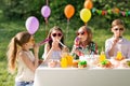 Happy kids blowing party horns at summer birthday