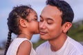 Holidays, children and asian family concept -portrait of a little girl kissing her dad on cheek. Royalty Free Stock Photo