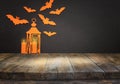 Holidays concept of Halloween. Empty rustic table in front of bats and lantern background. Ready for product display montage