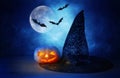 Holidays concept of Halloween . Pumpkin and witch hat over wooden table at night scary, haunted and misty forest Royalty Free Stock Photo