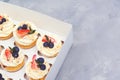 Holidays cupcakes with strawberry and blueberry, close up. Cupcakes packaging, delivery box on grey background. Gift box with