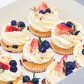 Holidays cupcakes with strawberry and blueberry, close up. Sweet shop. Present box full of fruit cupcakes