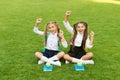 Holidays has begun. Happy children celebrate holidays outdoors. Little girls sit on green grass. School holidays. Summer