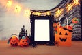 Holidays image of Halloween. Pumpkins, bats, treats, paper gift bag next to empty photo frame for mockup over wooden table. for Royalty Free Stock Photo