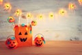 Holidays image of Halloween. Pumpkins, bats, treats, paper gift bag over wooden table