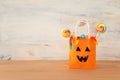 Holidays image of Halloween. Pumpkins, bats, treats, paper gift bag over wooden table