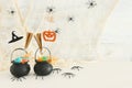 Holidays image of Halloween. Witcher cauldron, broom, candies and spiders over white wooden table