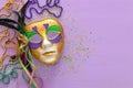 Holidays image of mardi gras masquarade, venetian mask and beads over purple background. view from above