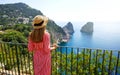 Holidays in Italy. Back view of beautiful girl in stunning Capri Island with Faraglioni sea stack and blue crystalline water on