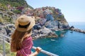 Holidays in Italy. Young traveler woman with hat and dress looking the amazing panoramic of Manarola village in Cinque Terre, Royalty Free Stock Photo