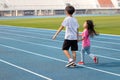 On holidays, kid boy and girl, brothers and sisters, are having fun playing outdoors in the field on the blue track.Outdoor