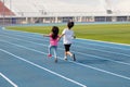 On holidays, kid boy and girl, brothers and sisters, are having fun playing outdoors in the field on the blue track.Outdoor