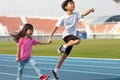 On holidays, kid boy and girl, brothers and sisters, are having fun playing outdoors in the field on the blue track.Outdoor