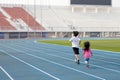 On holidays, kid boy and girl, brothers and sisters, are having fun playing outdoors in the field on the blue track.Outdoor